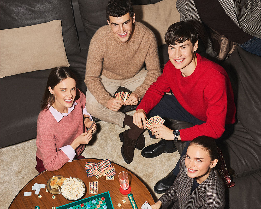 Czwórka przyjaciół gra w karty i spędza czas razem w przytulnym wnętrzu.