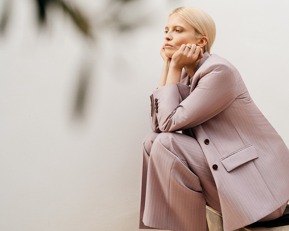 Kobieta w eleganckim garniturze w kolorze pudrowym marki Vistula.