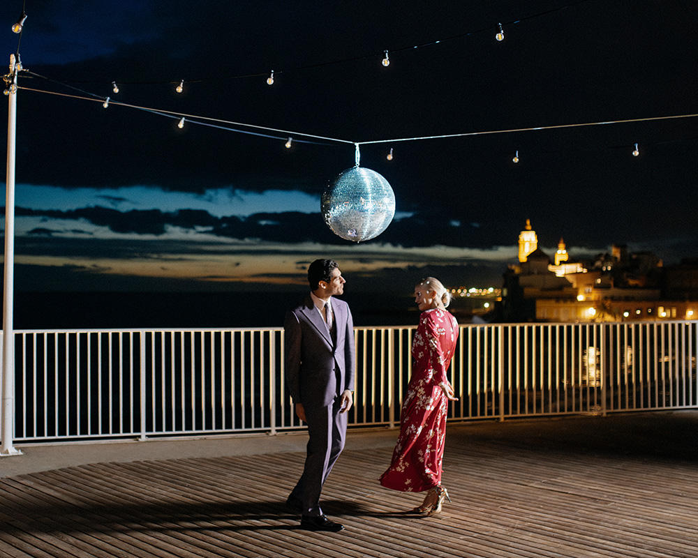 Para tańcząca pod dyskotekową kulą na tle nocnego nieba.