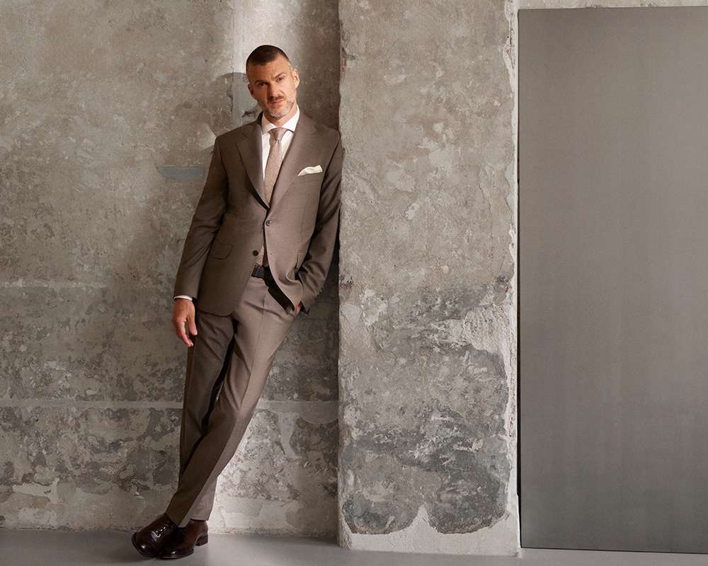 Mężczyzna w garniturze marki Vistula opierający się o ścianie.