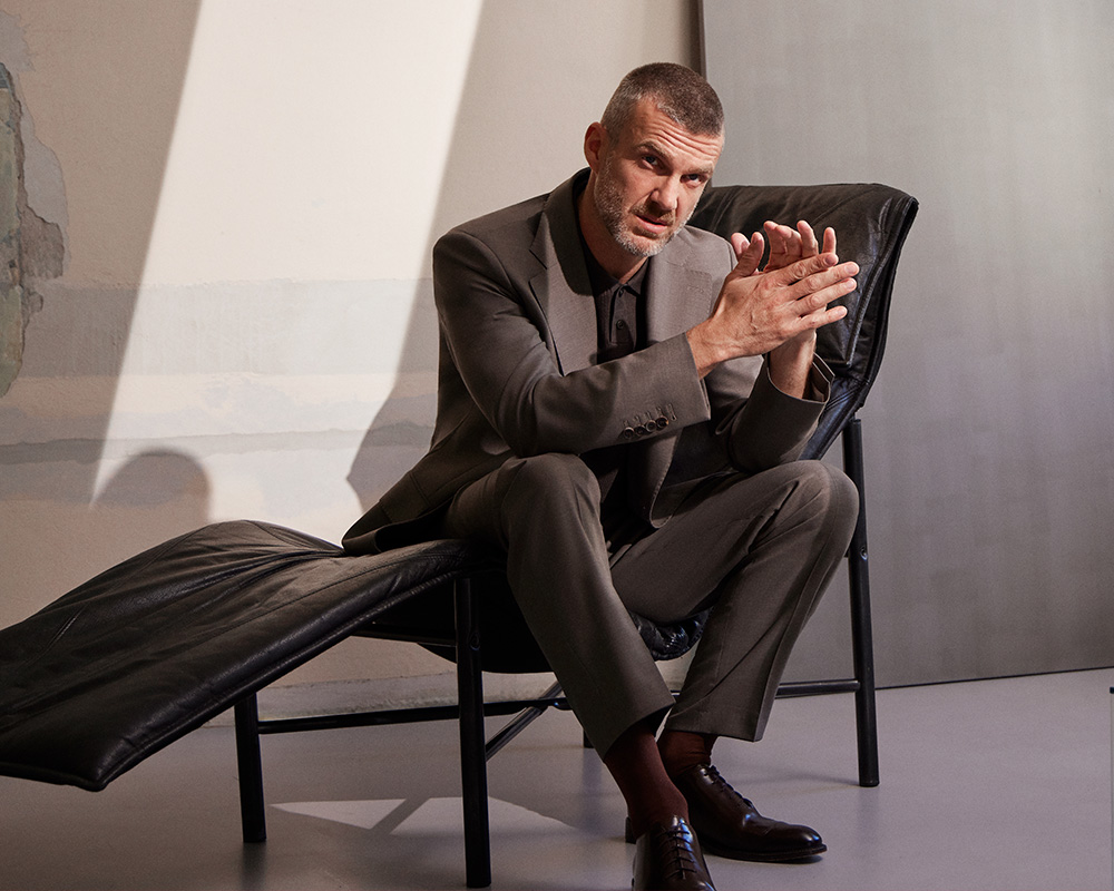 Mężczyzna w eleganckim garniturze siedzi na nowoczesnym fotelu