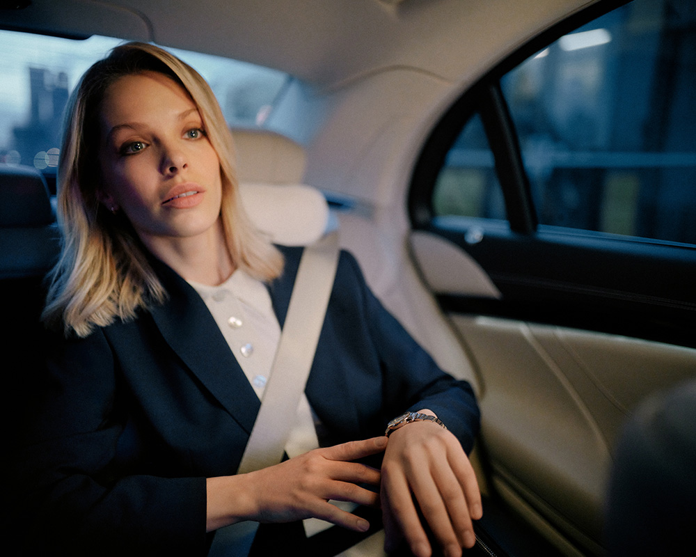 Kobieta w biznesowym stroju siedzi na tylnym siedzeniu samochodu.