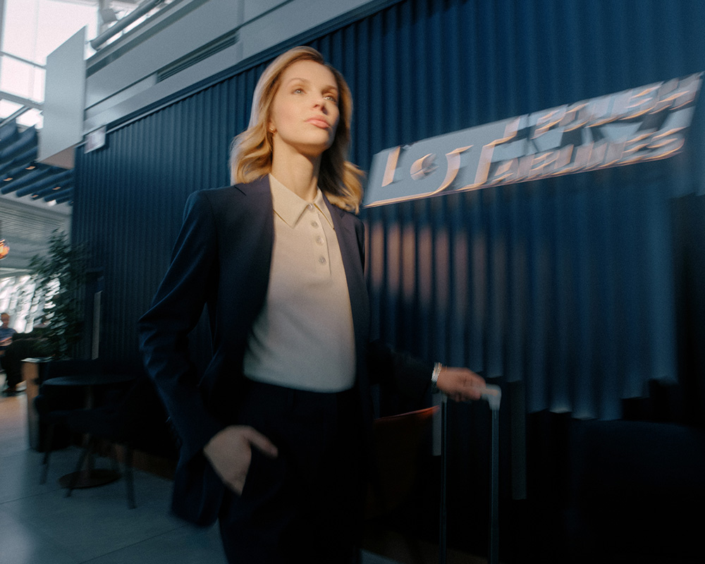 Kobieta z walizką idzie przez lotnisko.